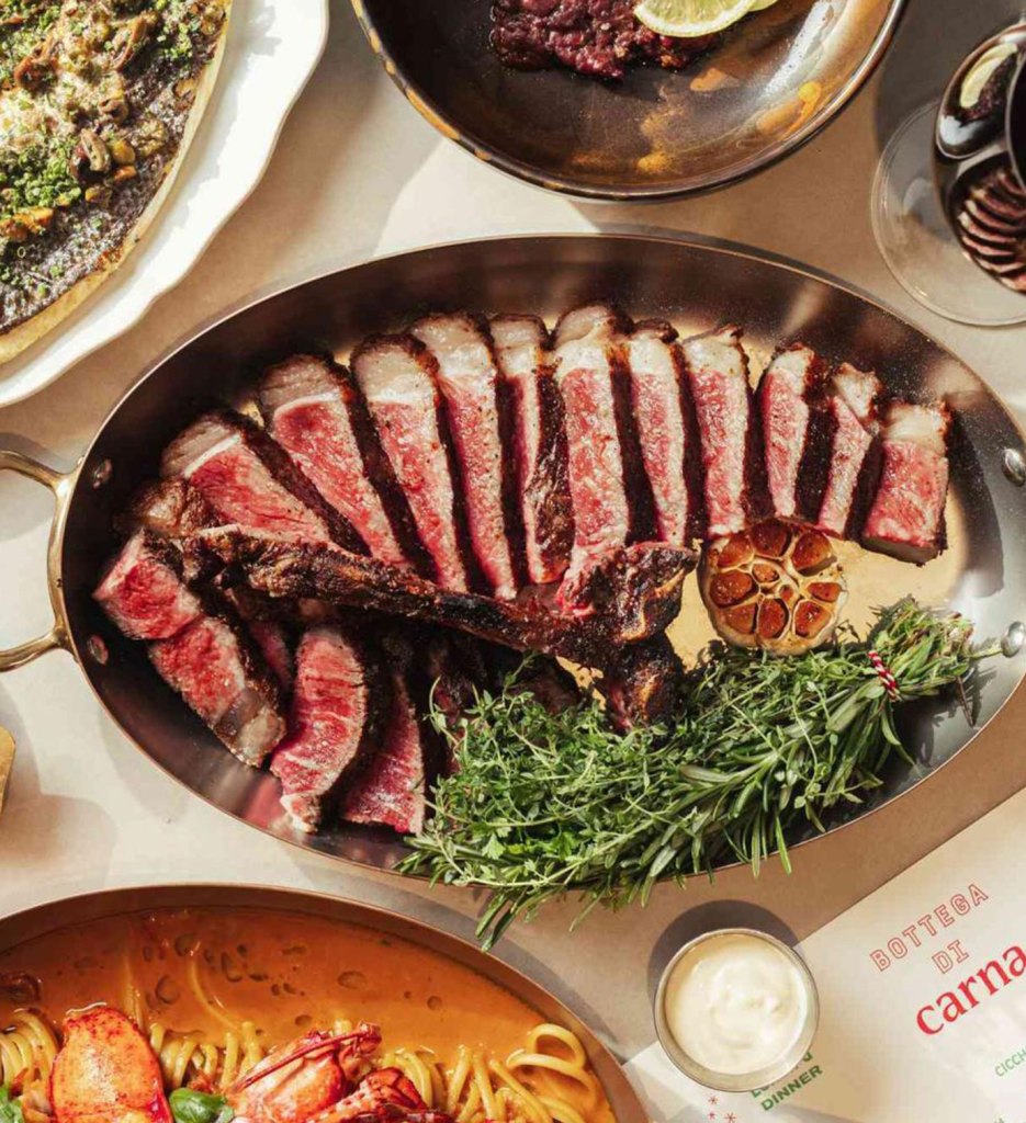 plated steak that is cooked rare on a table with other plates surrounding it