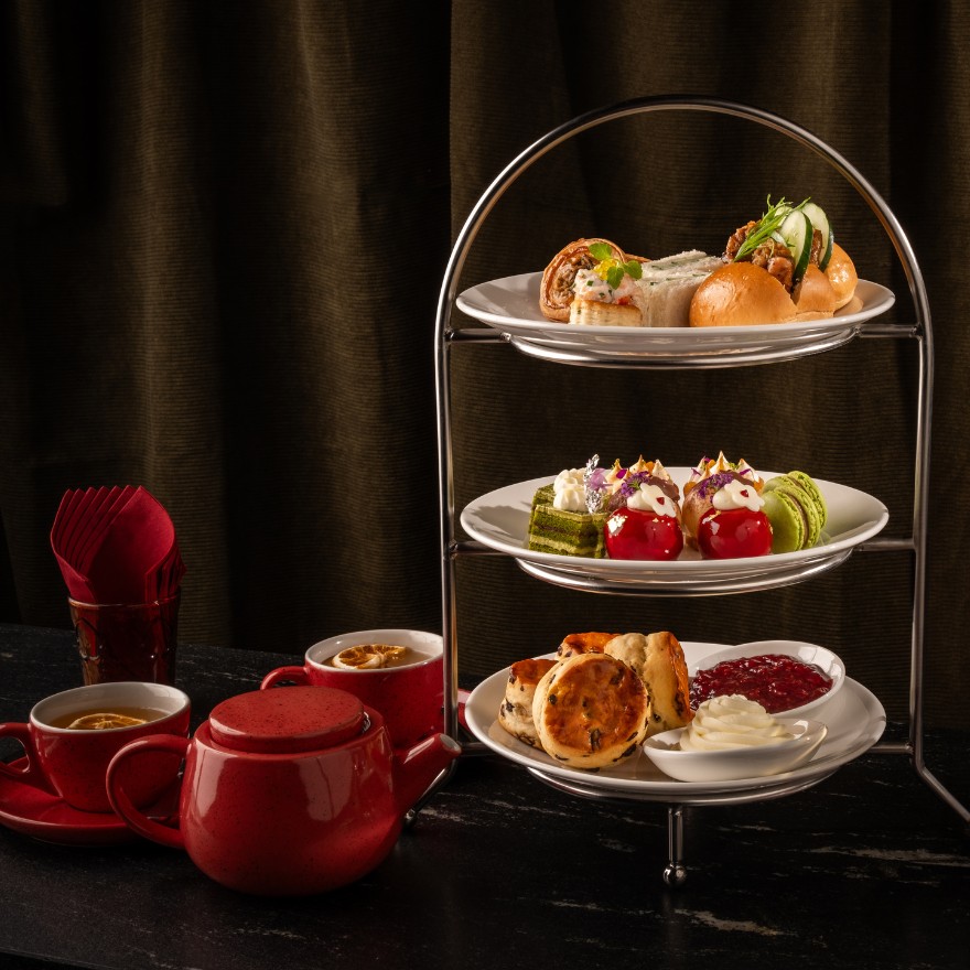 Tea tray with pastries and tea sandwiches with red pot of tea and tea cups