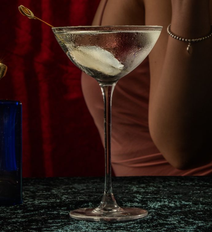 Close up shot of a martini with a garnish and woman's body in the background