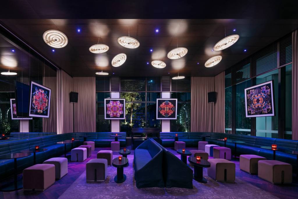 Stylish lounge/bar with banquet and pouf seating in blue and purple and glowing disc lighting above head