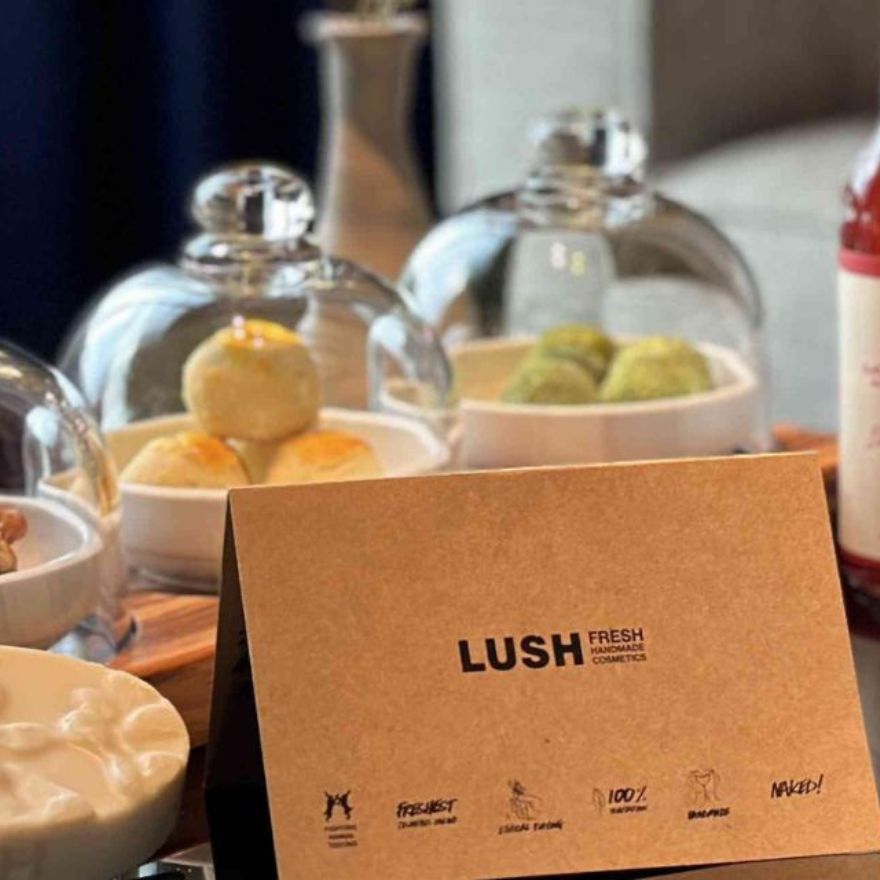 三个玻璃展示柜，内含浴球、写着“LUSH”字样的棕色卡片，背景是数个瓶子