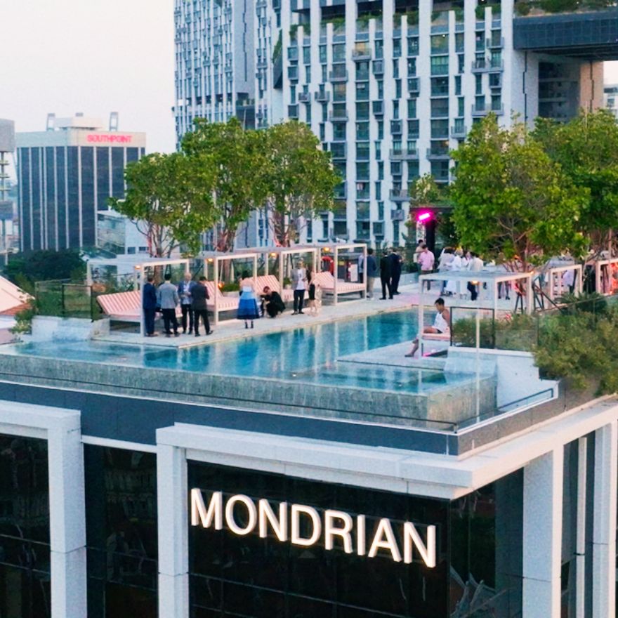 Rooftop pool with trees and lush plants and people enjoying a party