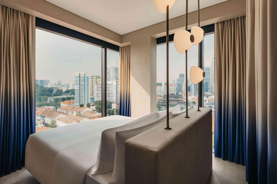 Mondrian Singapore guest room with blue and beige curtains, overlooking the city