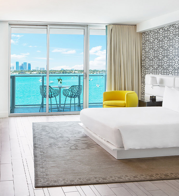 Hotel room with bed, chair, and window overlooking the water.