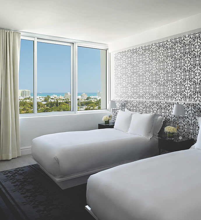 Two beds in a hotel room overlooking the ocean.