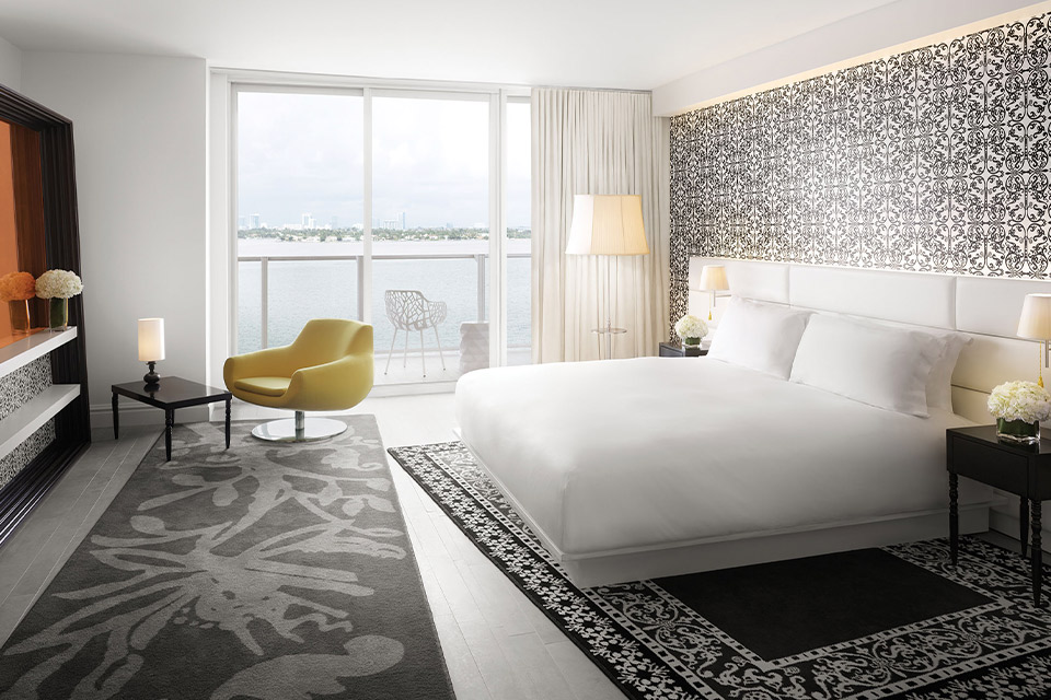 Hotel room with bed, chair, and window facing water.