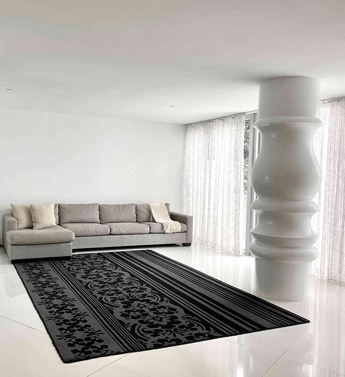 A modern living room with a black rug, grey couch and oversized column.