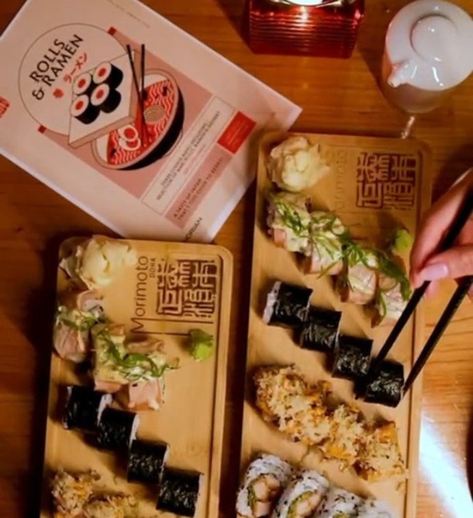 Platos de sushi y un libro de Rolls & Ramen en Morimoto Doha