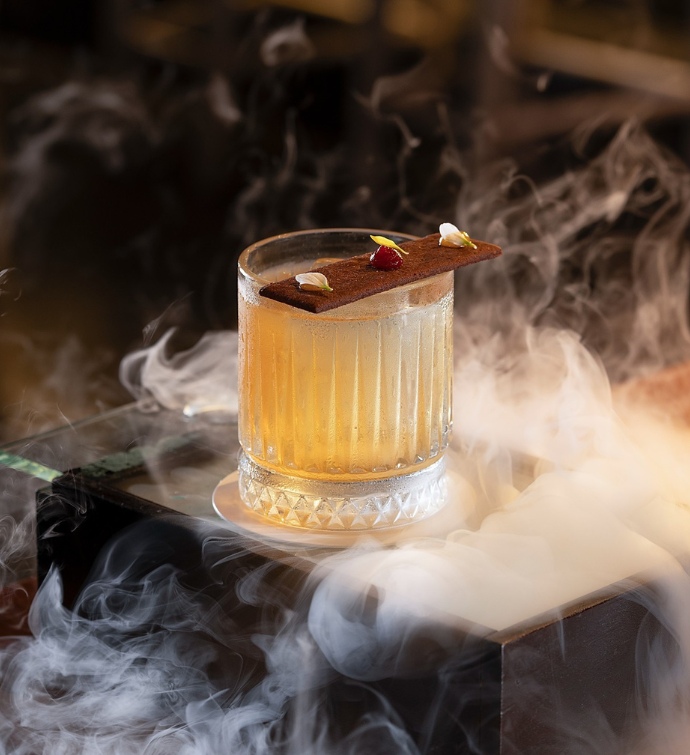 Yellow cocktail with smoke surrounding it