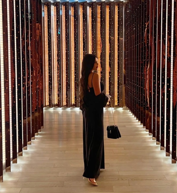 Woman in a long, black dress in the hallway at Mondrian Doha