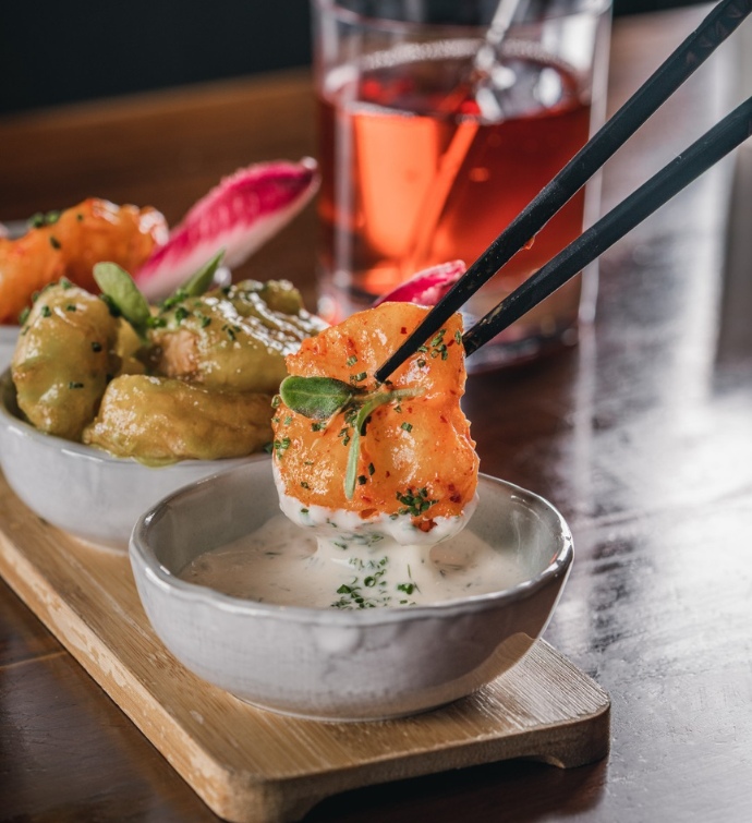 Piece of food being dipped in a sauce at Morimoto Doha