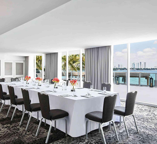 a meeting space set up as a boardroom with floor to ceiling windows and a view of the bay