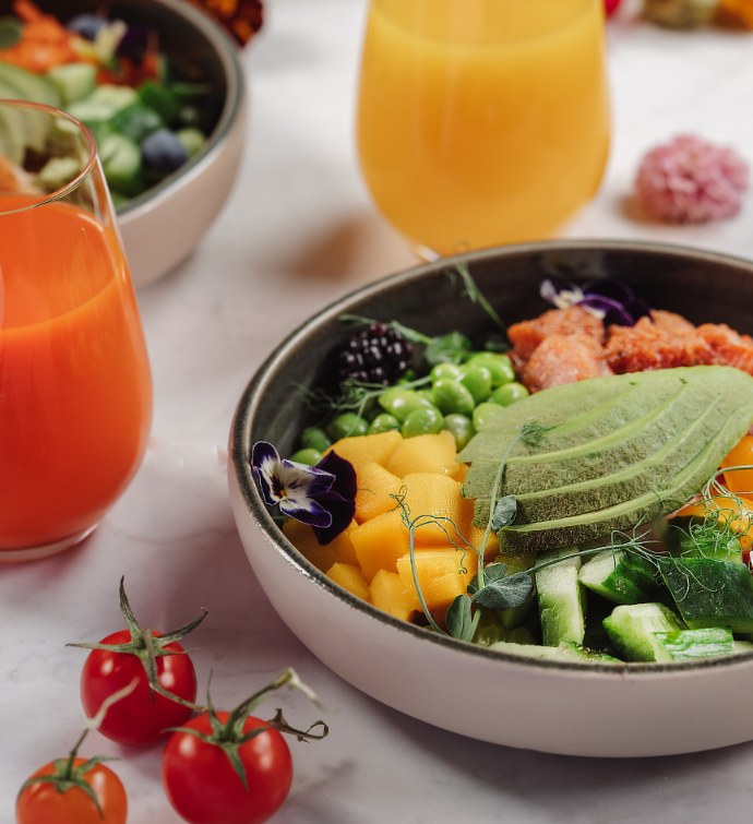 Bol con aguacate, moras y pepinos acompañado de zumos recién hechos