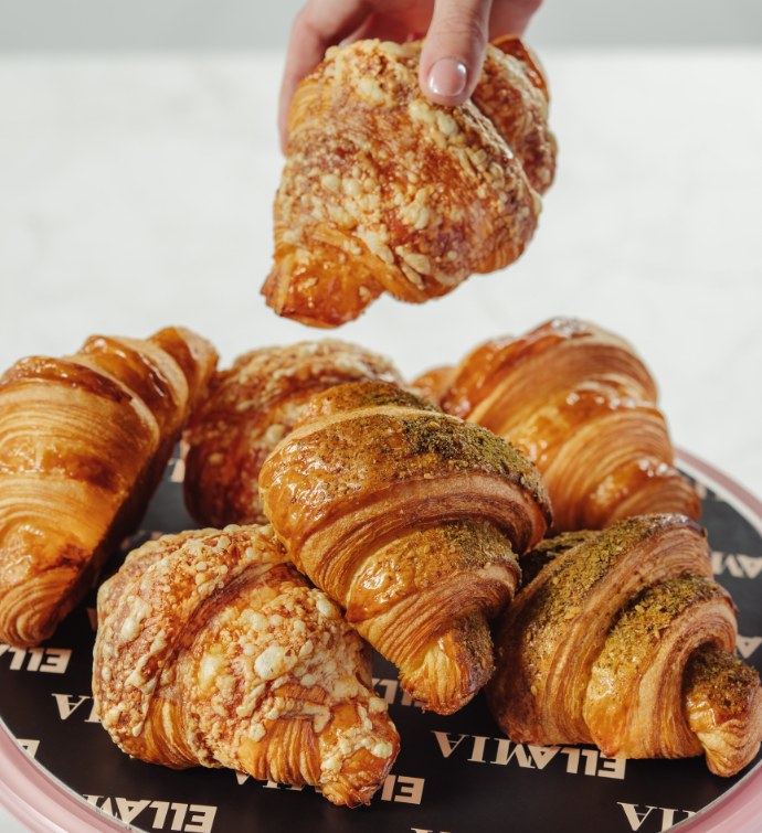 Main choisissant un croissant dans une assiette de croissants