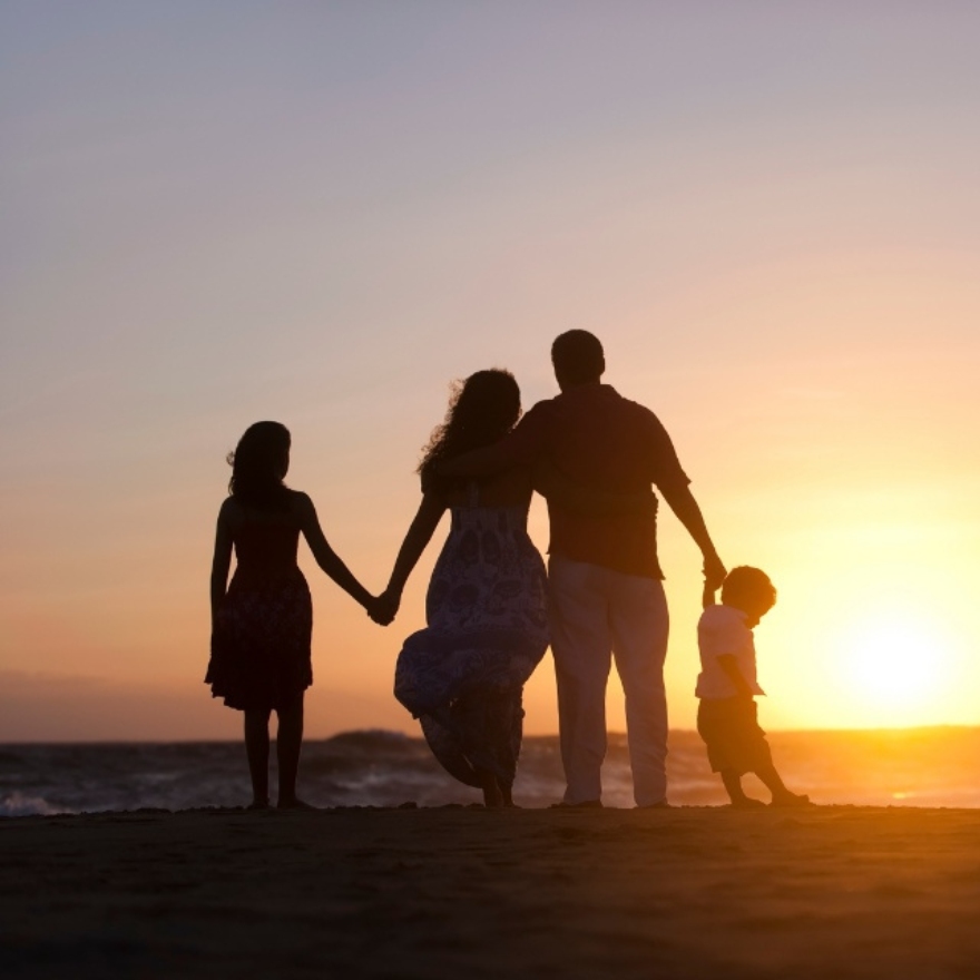 Famille de quatre personnes sur une plage au coucher du soleil