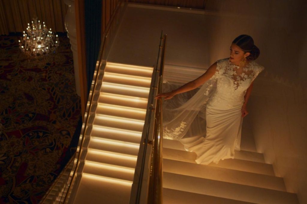 Femme en robe de mariée montant un escalier illuminé