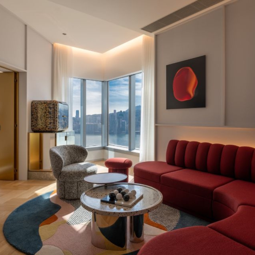 Living area with a red wraparound couch, grey chair and harbour views