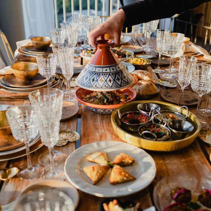 una mesa llena de deliciosas tapas y comida servida en platos de colores con copas de champán de cristal y platos dorados