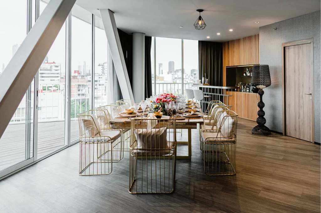 una pequeña mesa de comedor instalada en un ático con hermosas flores y arreglos de mesa