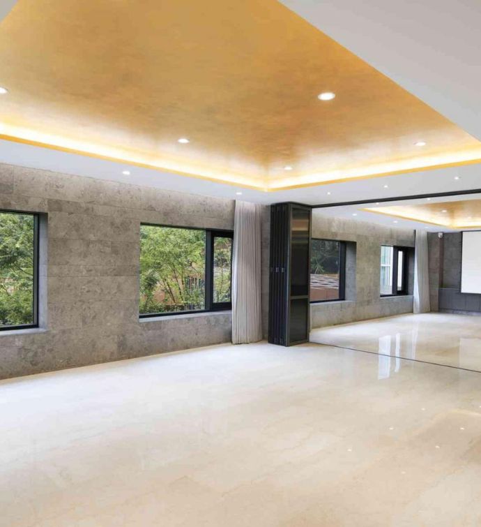 Large event space empty with wooden floors, gray walls, and yellow/gold ceiling