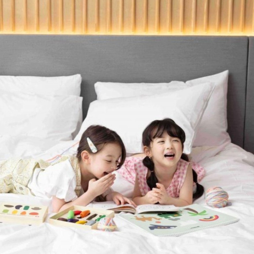 Two girls sitting and laughing on a bed at Mondrian Seoul