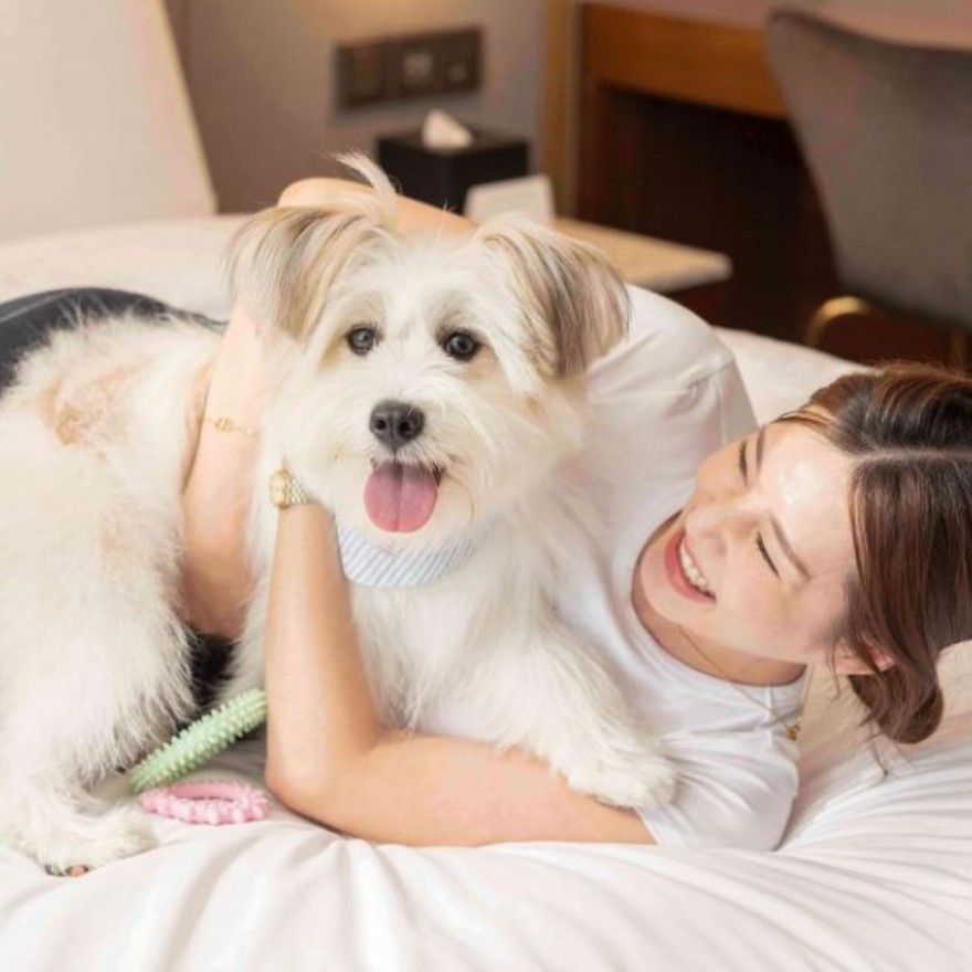 Woman hugging a dog on a bed at Mondrian Seoul Itaewon