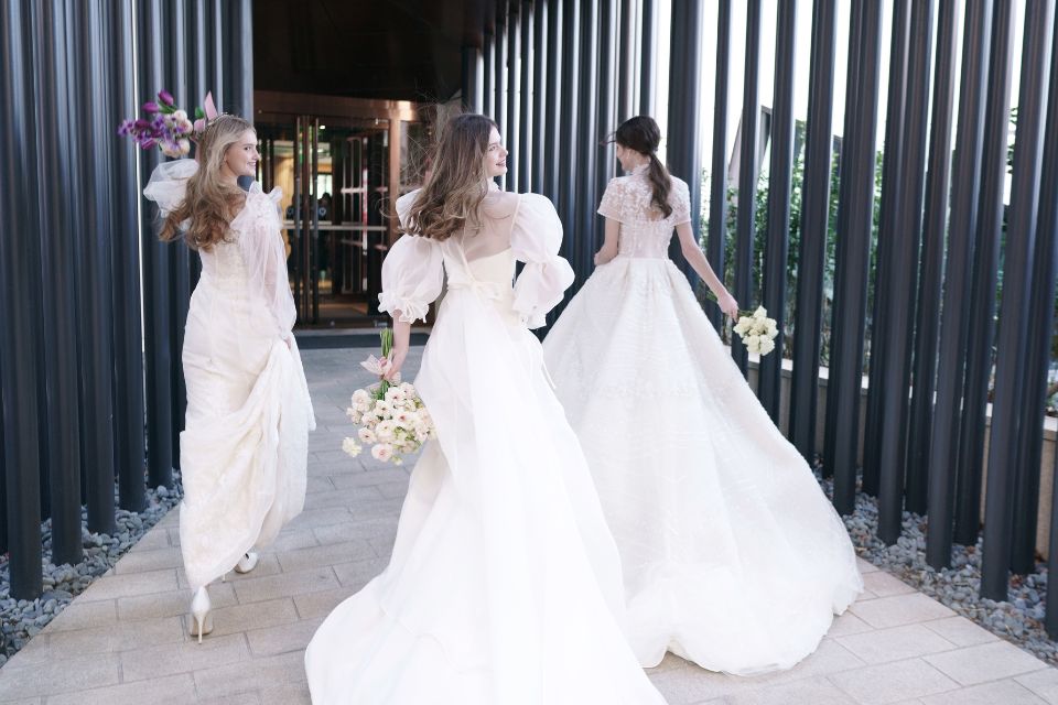 Three brides with bouquets in hand running down a hallway