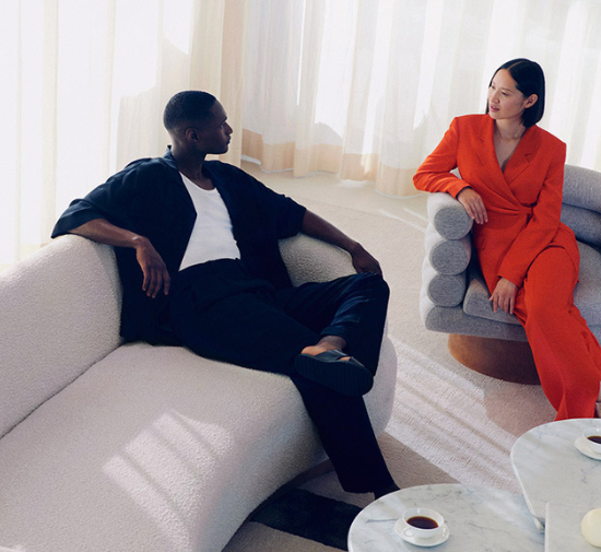 man and woman sitting on sofa and chari in a bright room