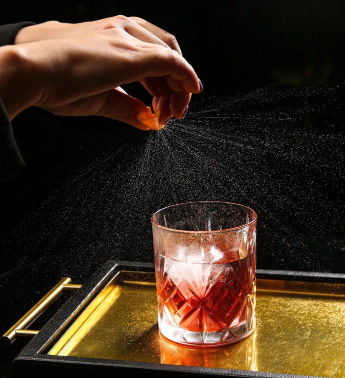 Main versant un spritz dans un cocktail rouge 