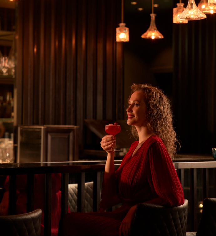 Femme en robe rouge tenant un cocktail 