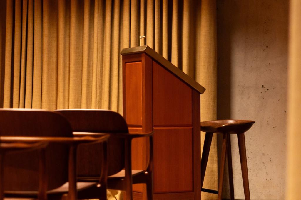 Podium avec un tabouret derrière, faisant face aux sièges