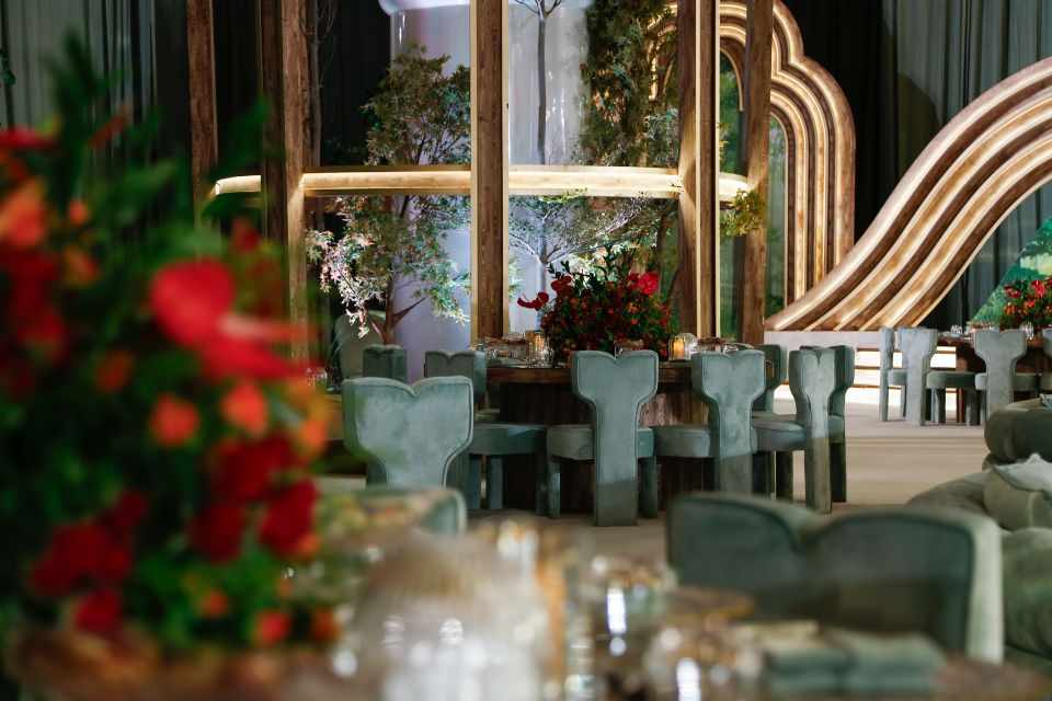 Green velvet seats with round tables and red flowers in a dining room