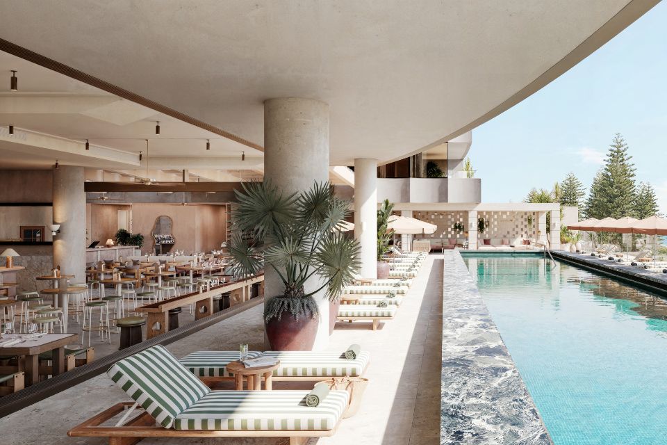 Large rectangular pool with striped lounge chairs on a pool patio decorated with large palm plants and a dining room in the background