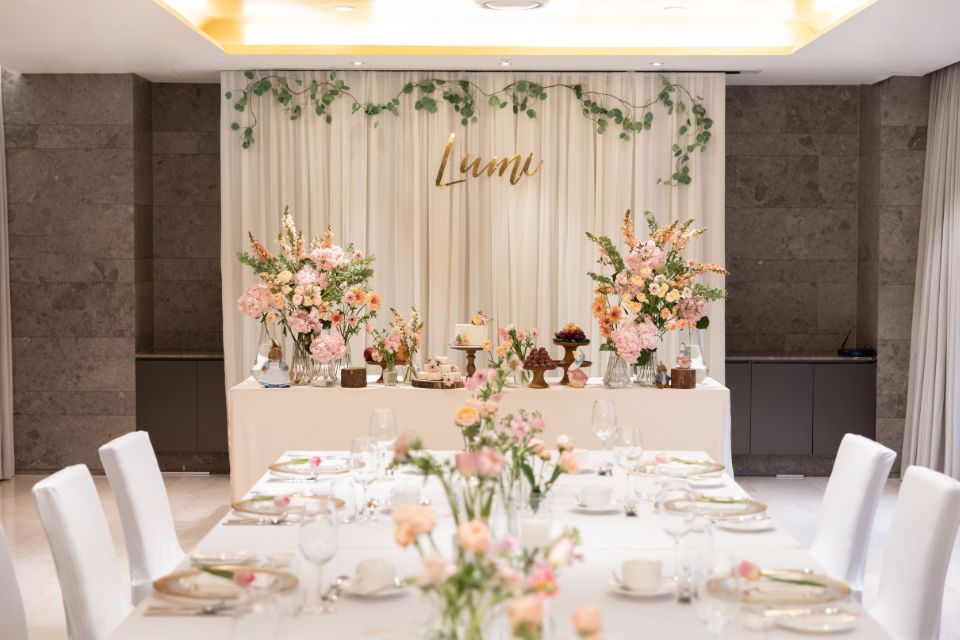 First birthday party set up with white chairs, tables, and pink flowers