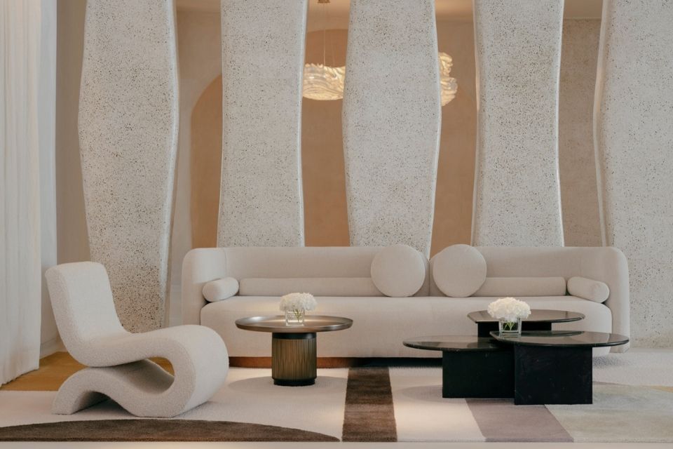 Sleek, modern lobby with white sofa and white chair with two round metal tables and a geometric patterned rug