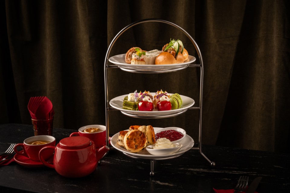 Tea tray with pastries and tea sandwiches with red pot of tea and tea cups