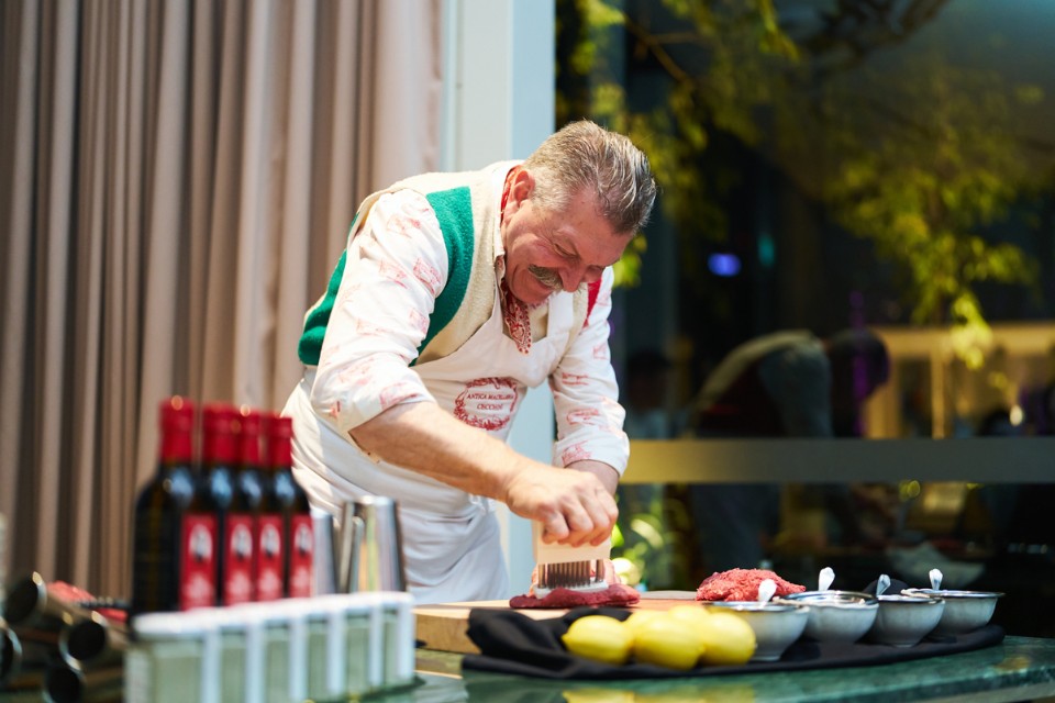 Male chef leaning over a table making beef tartare