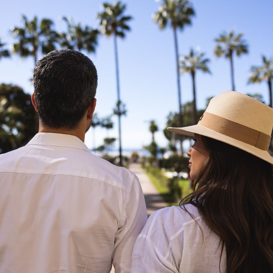 Back of man and woman looking out to blue sky and palm trees