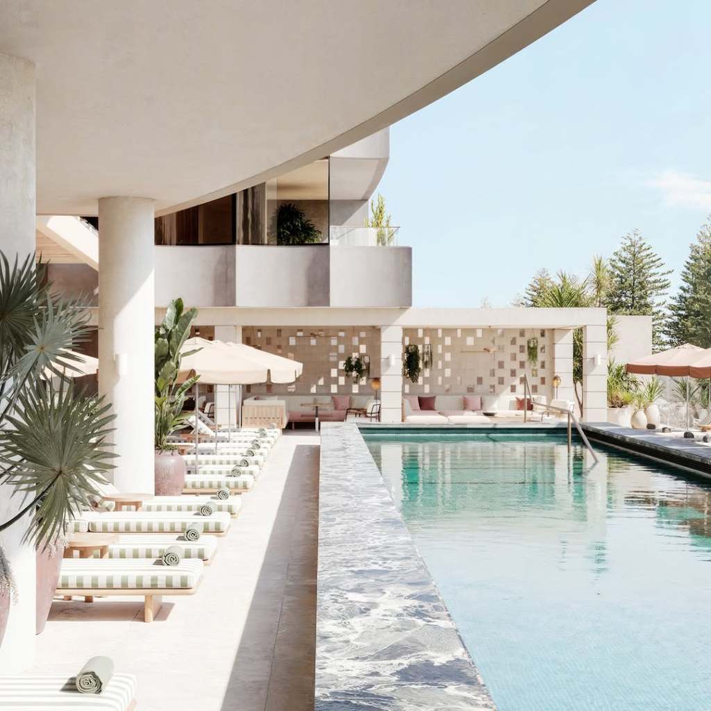 Large pool with striped chaise lounges and cabanas surrounding it