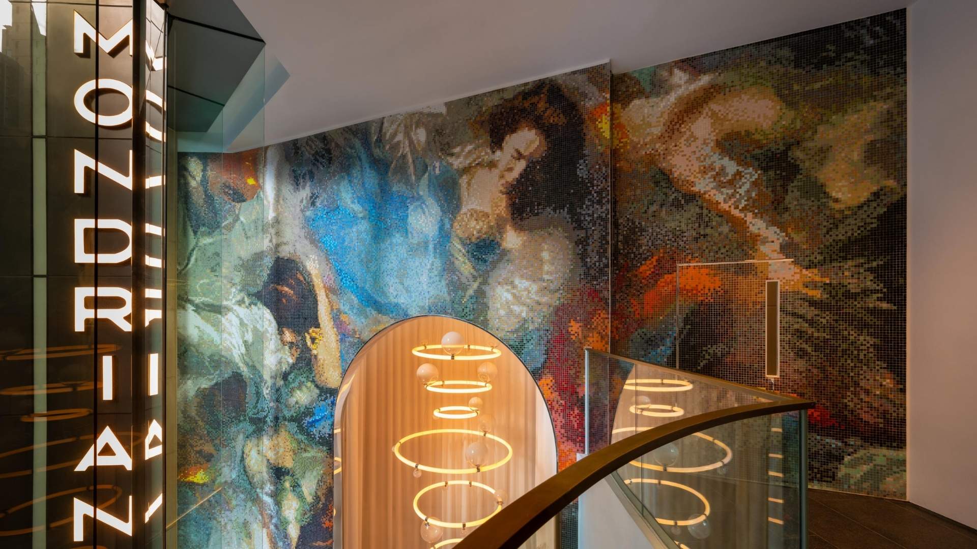 Entrance of hotel with watercolor painted walls and lit up sign that reads 'MONDRIAN'