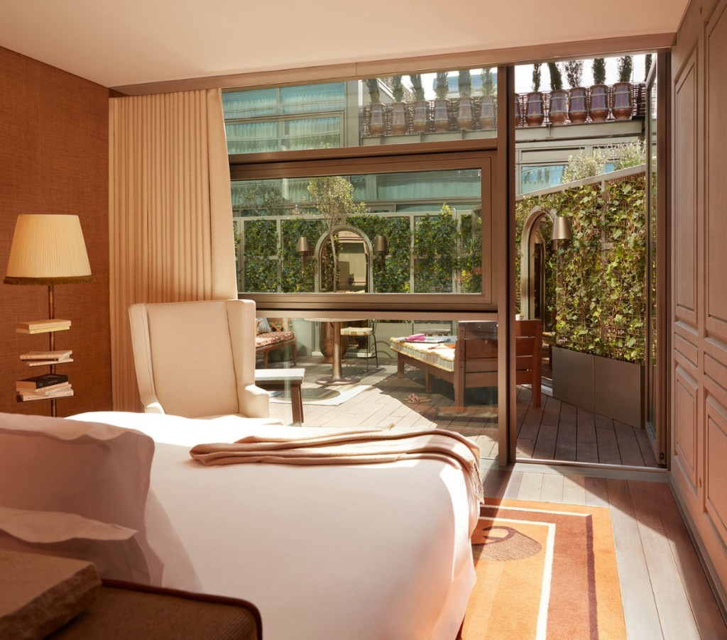 Hotel room with white bed and door leading to an outdoor garden