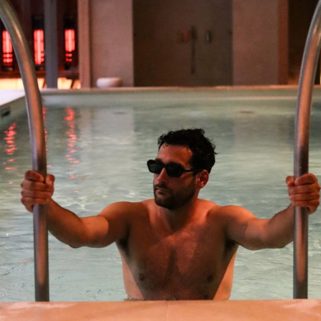 Man in sunglasses climbing out of a pool