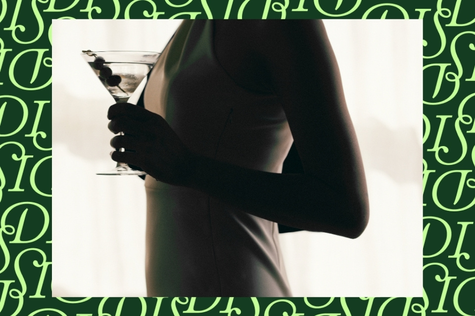 Woman holding a martini with olives on a green background