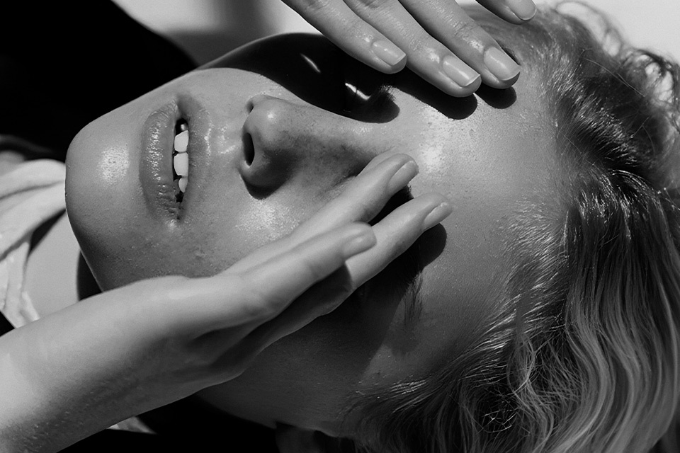 Black and white image of a woman covering her eyes with her hands