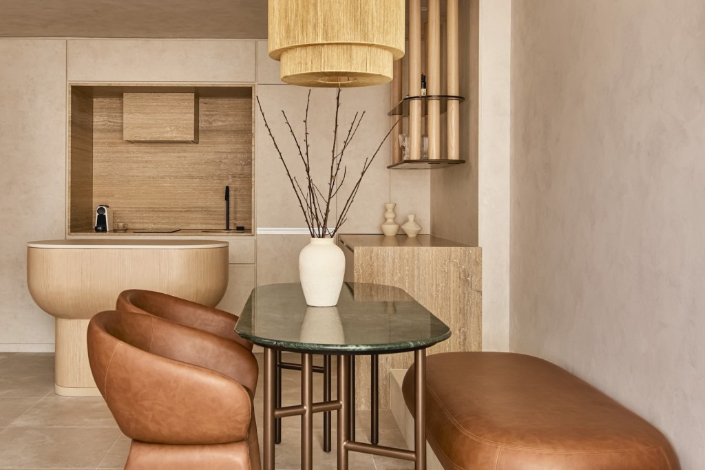 Oval dining table with pot and twigs on top and leather bench with leather dining chairs