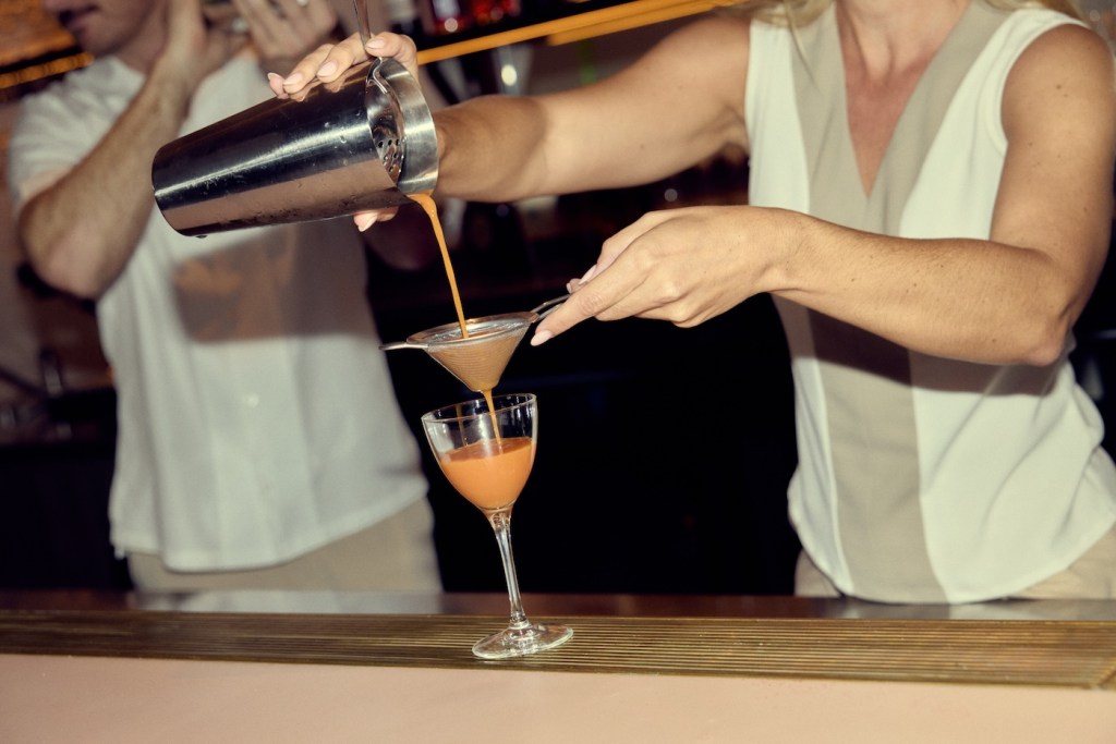 Pink cocktail being poured into a glass