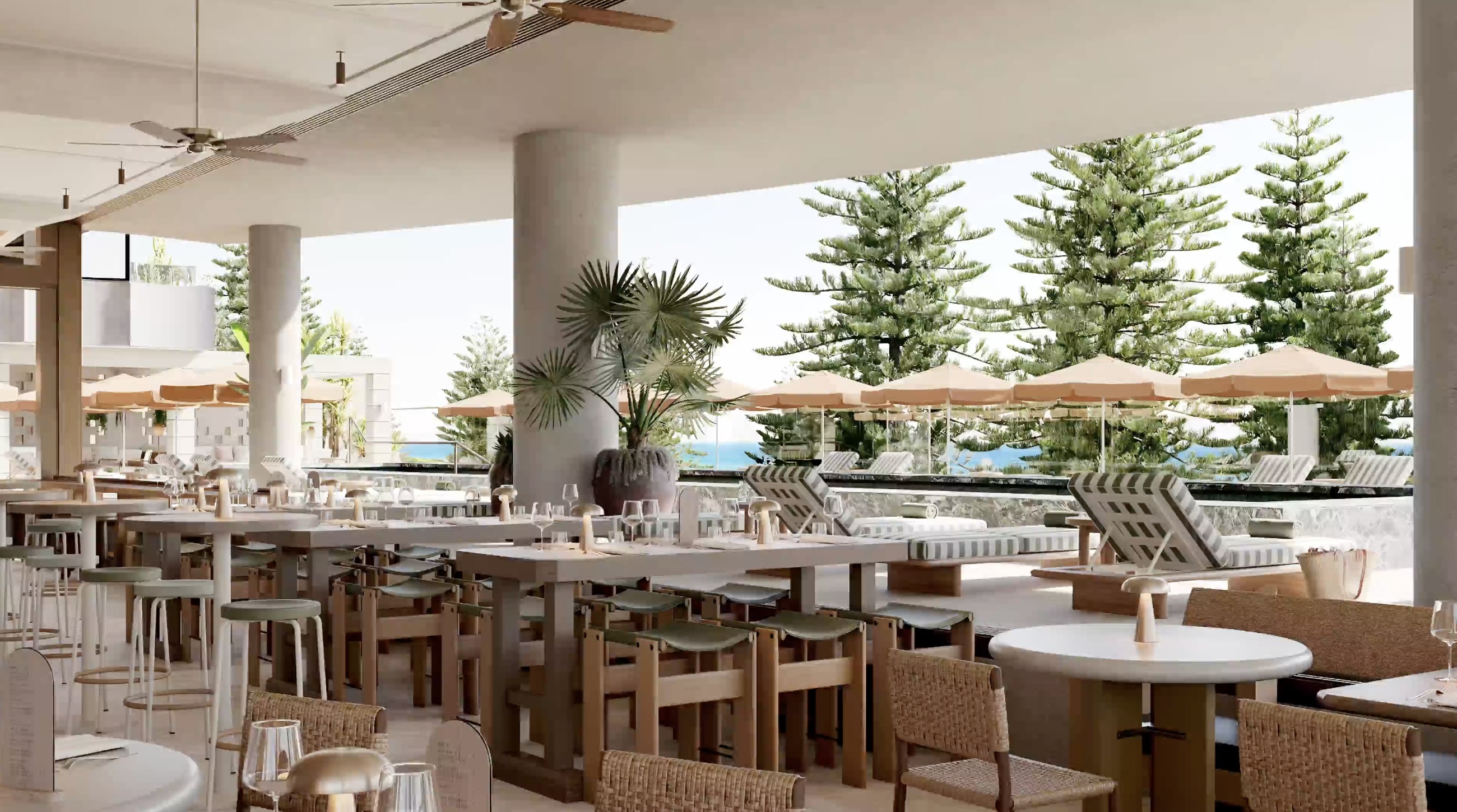 Large indoor/outdoor dining room with pool and umbrellas in the background