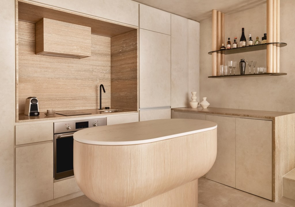 Light wooden kitchen island with sink, cupboard, and other kitchen appliances behind it