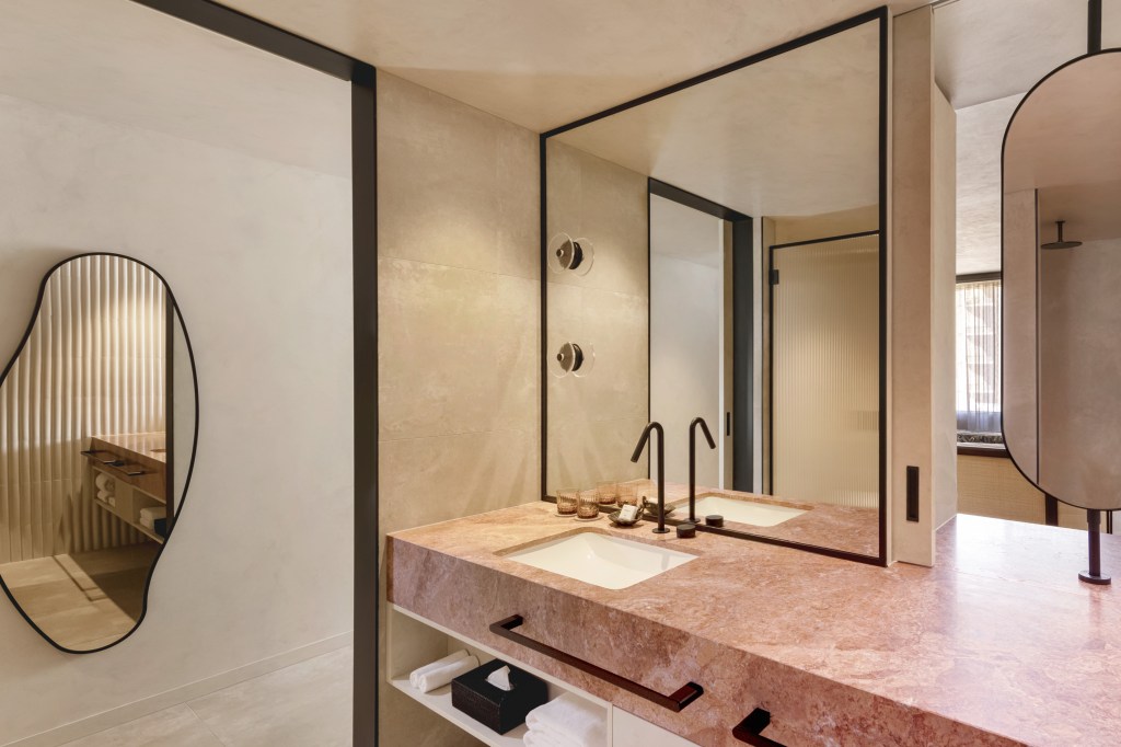 Bathroom sink with pink marble countertop and multiple mirrors