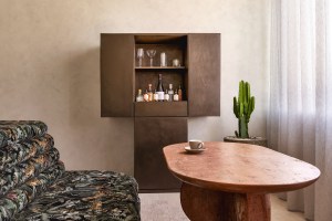 Patterned green sofa with dark wooden bar to the right and a round wooden table